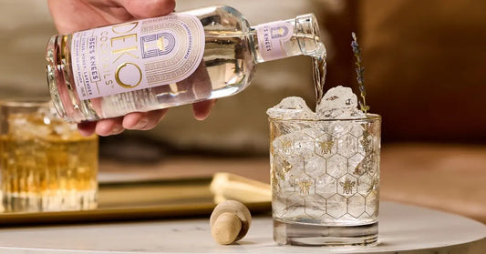 Bee's Knees cocktail being poured over ice in a decorative glass with a lavender garnish