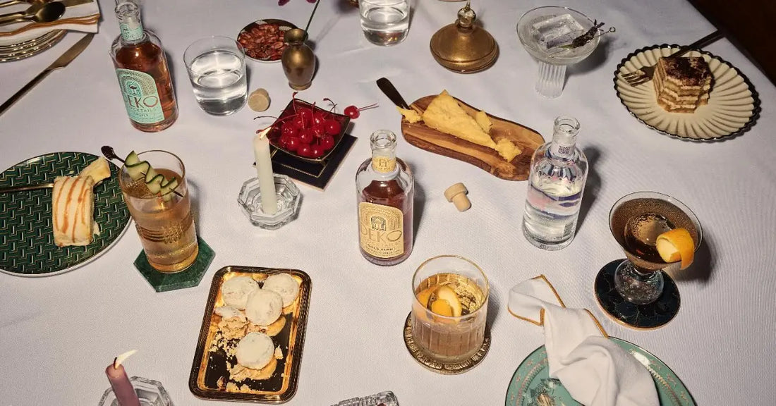 Classic gold rush cocktail on a dinner table surrounded by desserts, snacks, and elegant glassware.