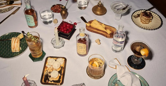 Classic gold rush cocktail on a dinner table surrounded by desserts, snacks, and elegant glassware.
