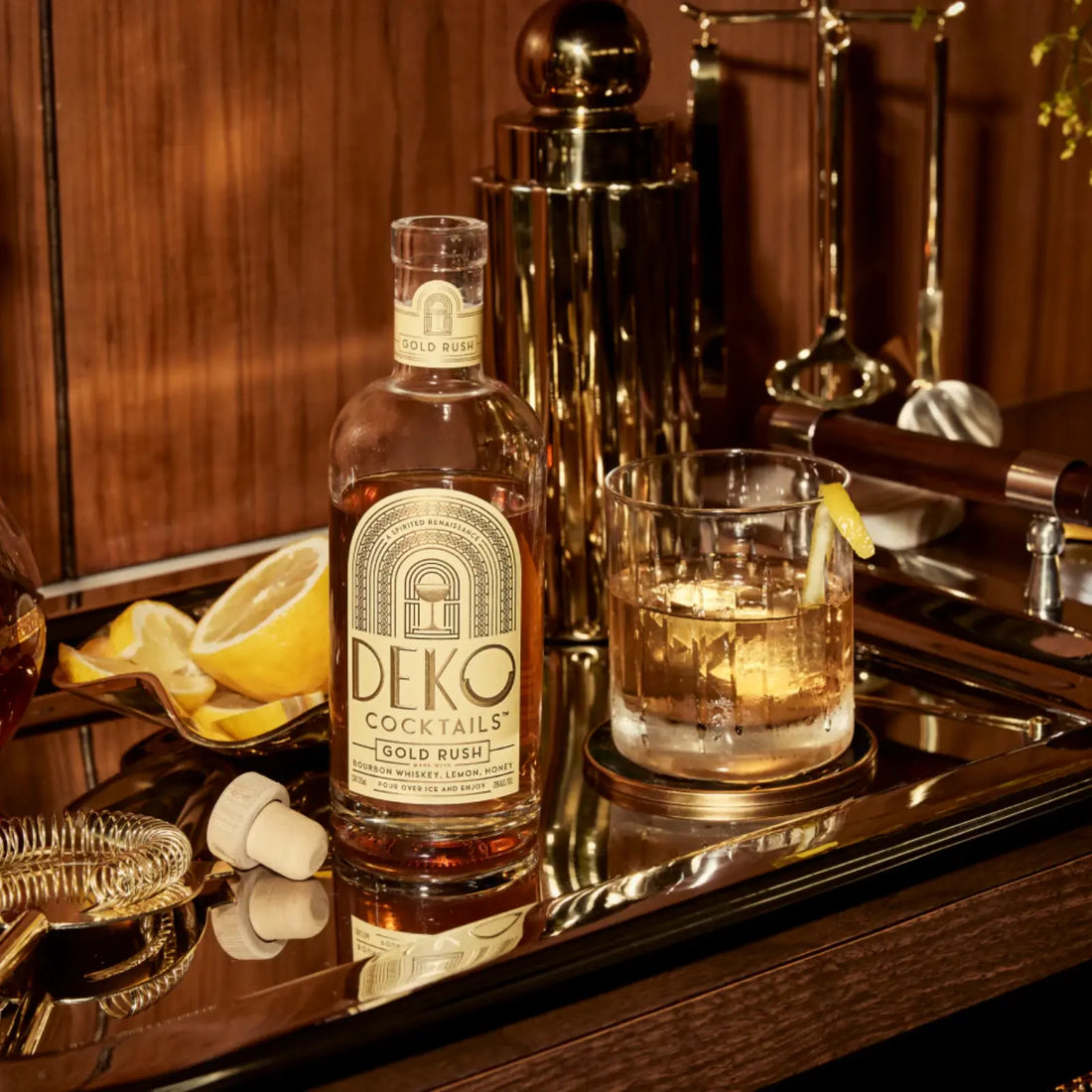 Gold Rush cocktail bottle on a luxurious bar setup with a glass of the drink and fresh lemon