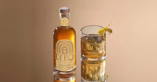 Premade cocktails bottle and glass with lemon twist garnish displayed on reflective surface
