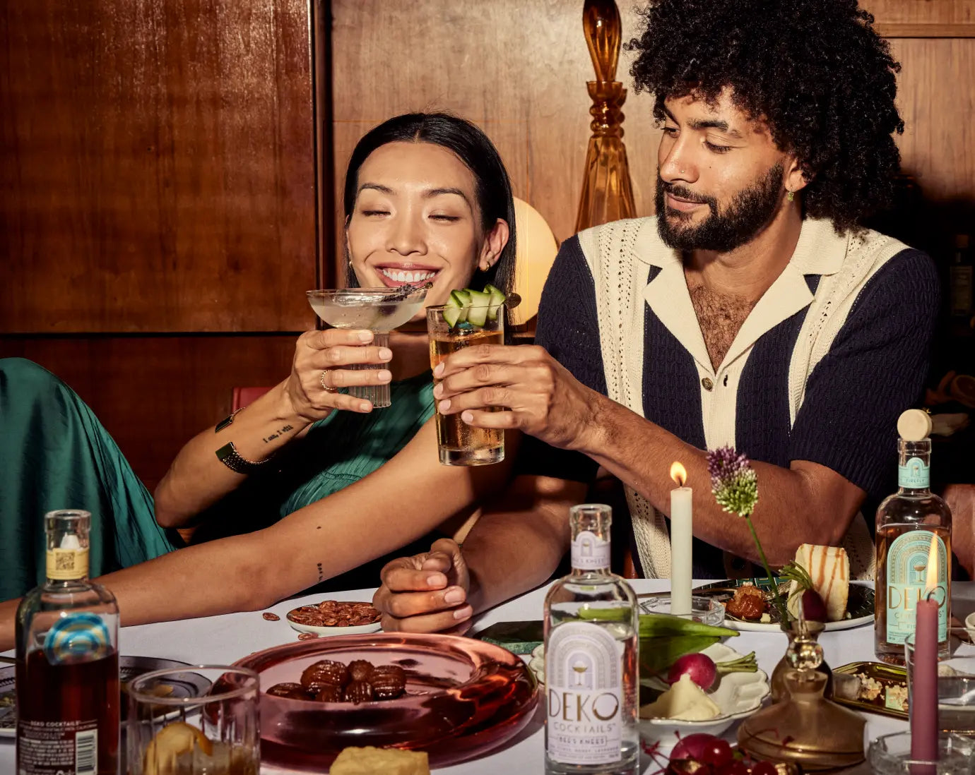 High end cocktails being enjoyed by a stylish couple at a candlelit dinner table featuring Deko bottled drinks and elegant glassware.