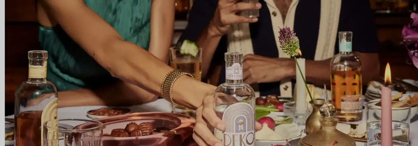 Ready to drink bottled cocktails on a lively dinner table with Deko bottles, garnished drinks, and shared appetizers.