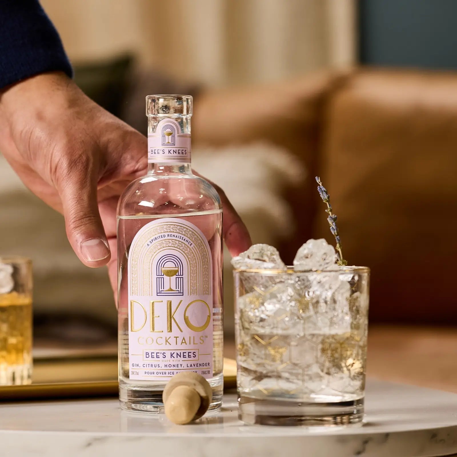 Premade alcohol drinks featuring a bottle of Bee's Knees cocktail with a matching glass garnished with lavender.
