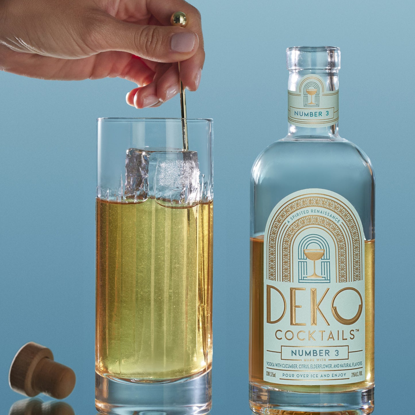 Firefly cocktail featuring a bottle of Deko Cocktails Number 3 made with vodka, cucumber, citrus, elderflower, and natural flavors, shown next to a tall glass with ice being stirred.