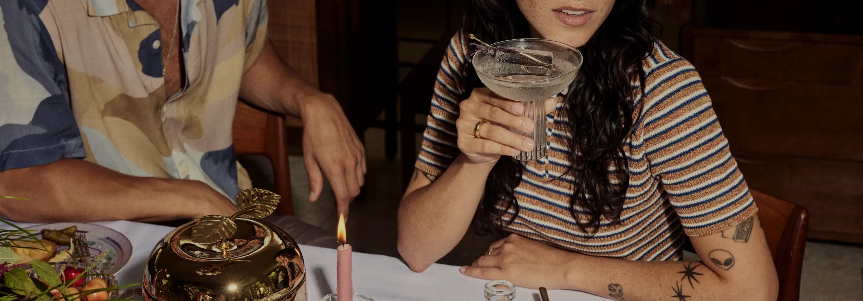 Cocktail premade and served in a stylish glass held by a woman at a candlelit dinner table.