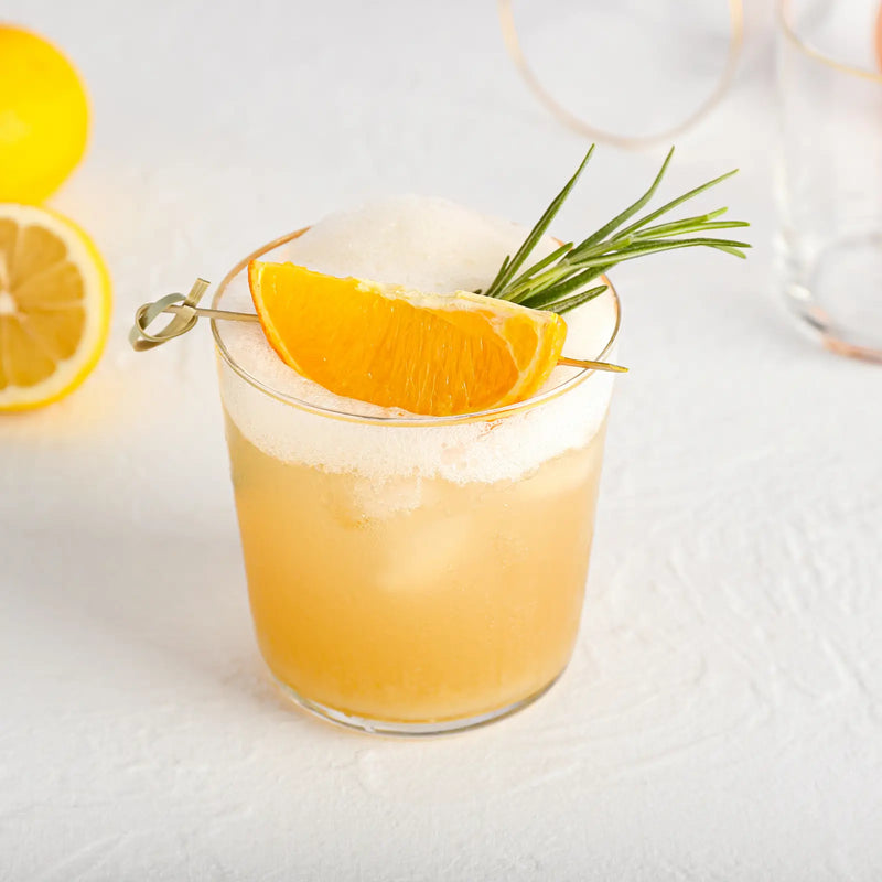 Foamy bourbon sour cocktail garnished with an orange wedge and rosemary sprig.