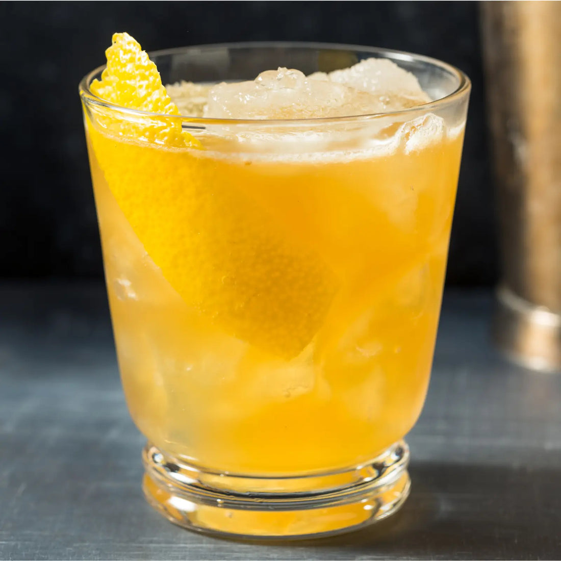 Close-up of a Gold Rush cocktail featuring a lemon garnish and golden-hued drink in a clear glass