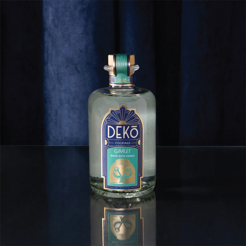 DEKO Cocktails vodka Gimlet, a bottled gimlet cocktail, on a reflective surface against blue velvet.