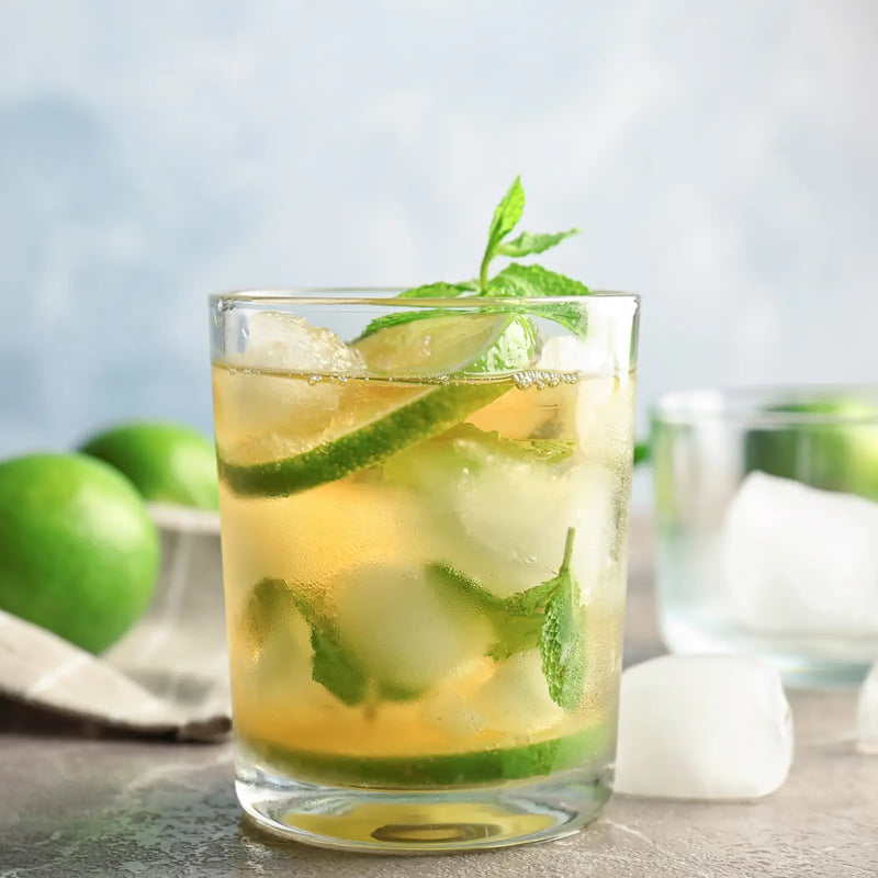 Close-up of a classic mint julep with lime and mint, served chilled with ice on a light background