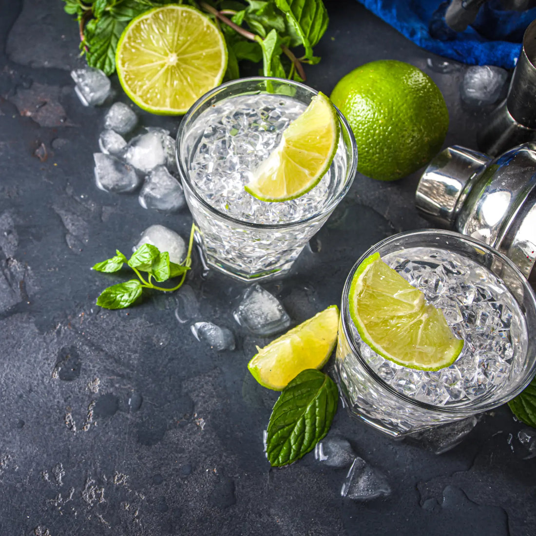 vodka lemonade cocktails served in short glasses with ice, fresh lime wedges, and mint leaves on a dark surface