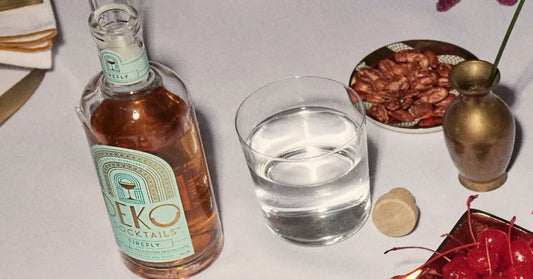 Best bottled cocktails from Deko displayed on a dinner table with snacks, a water glass, and cherries.