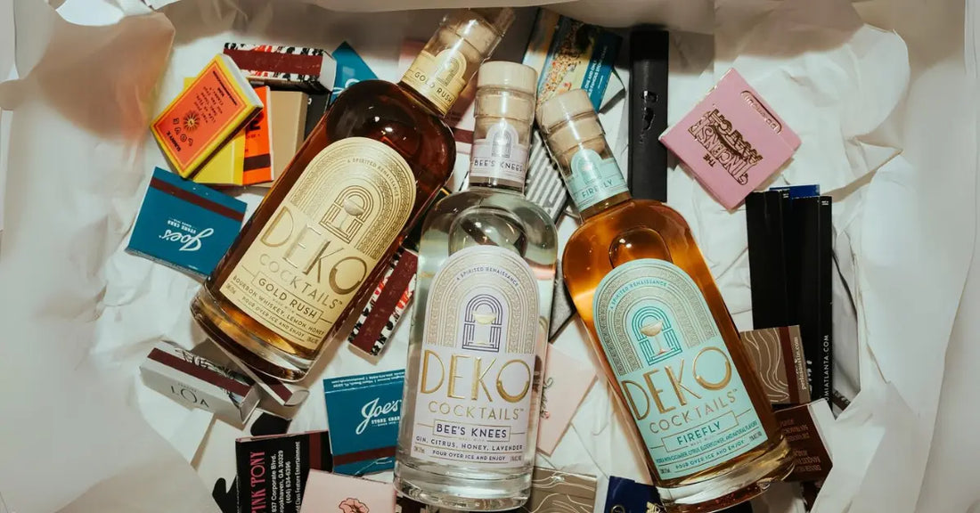 Bottled cocktails from Deko Cocktails, featuring Gold Rush, Bee’s Knees, and Firefly, displayed among colorful matchboxes