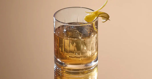 Bourbon honey cocktail served in a rocks glass over ice, garnished with a twisted lemon peel.