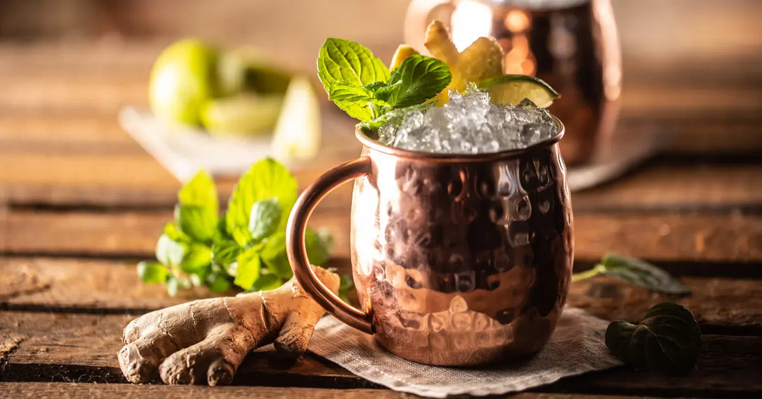 Flavored Moscow mule served in a copper mug with crushed ice, fresh mint, lime, and ginger on a rustic table