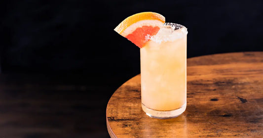 Paloma cocktail drink served in a tall glass with crushed ice, a salted rim, and a fresh grapefruit wedge garnish