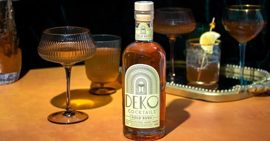 Small-batch cocktails like Deko’s Gold Rush elegantly served in vintage glassware on a golden table.