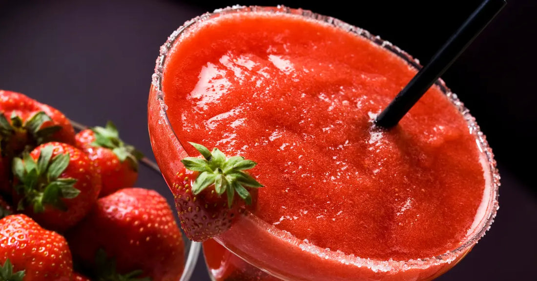 Strawberry daiquiri in a sugar-rimmed glass, garnished with fresh strawberries and served with a black straw.