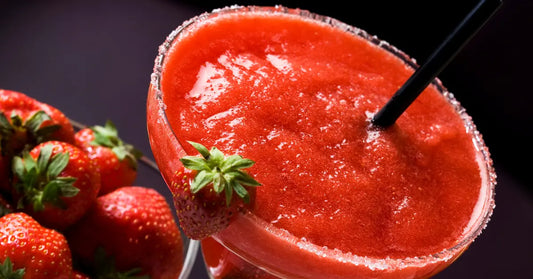 Strawberry daiquiri in a sugar-rimmed glass, garnished with fresh strawberries and served with a black straw.