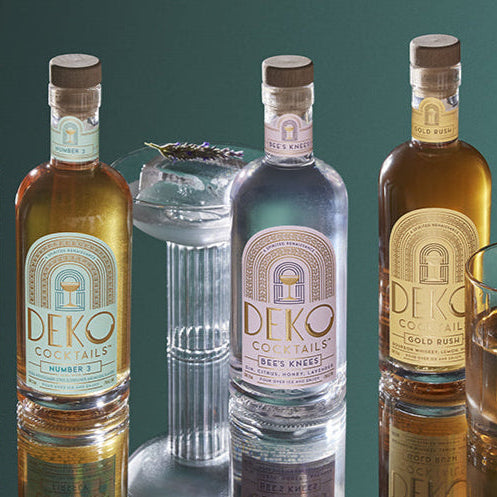 Premixed bottled cocktails from DEKO featuring Number 3, Bee’s Knees, and Gold Rush flavors in stylish glass bottles.